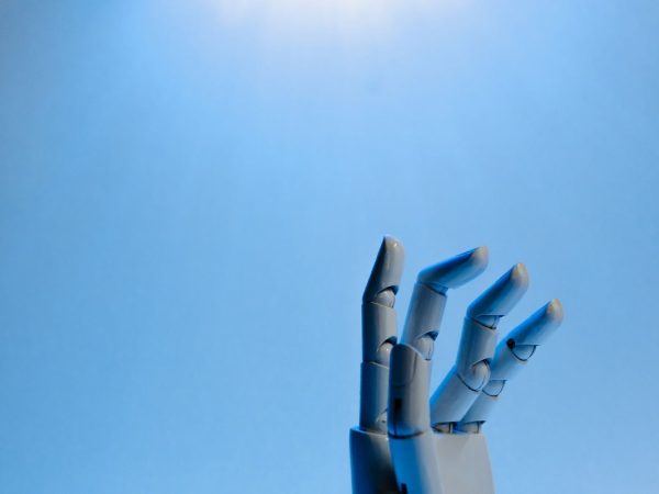 Mână robotică pe fundal albastru, reprezentativă pentru inteligența artificială